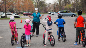 A WABA instructor speaks to three kids on bikes.